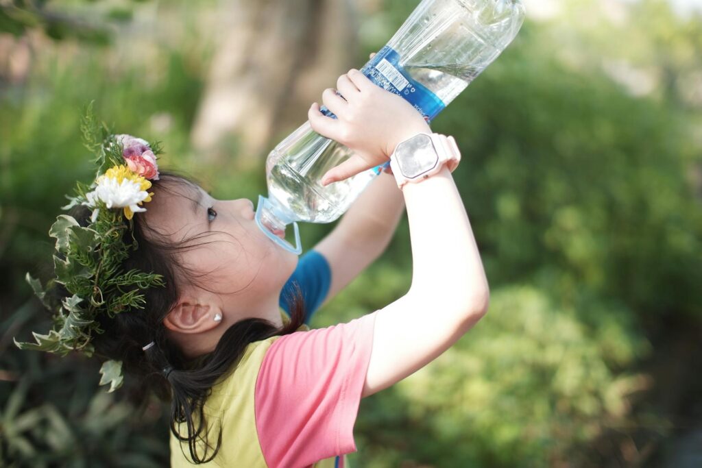 Little girl drinking water from bottle.